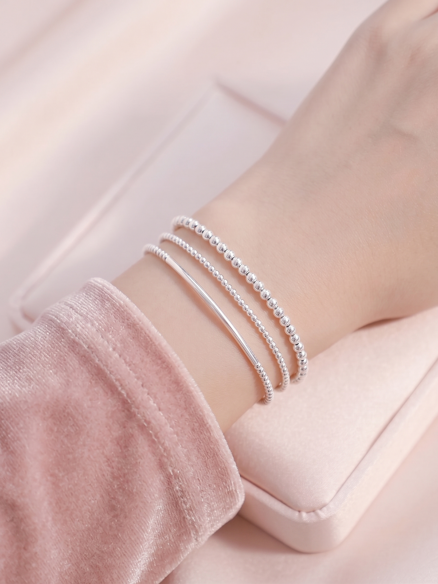 Stacked silver beaded stretch bracelets with smooth bars on wrist