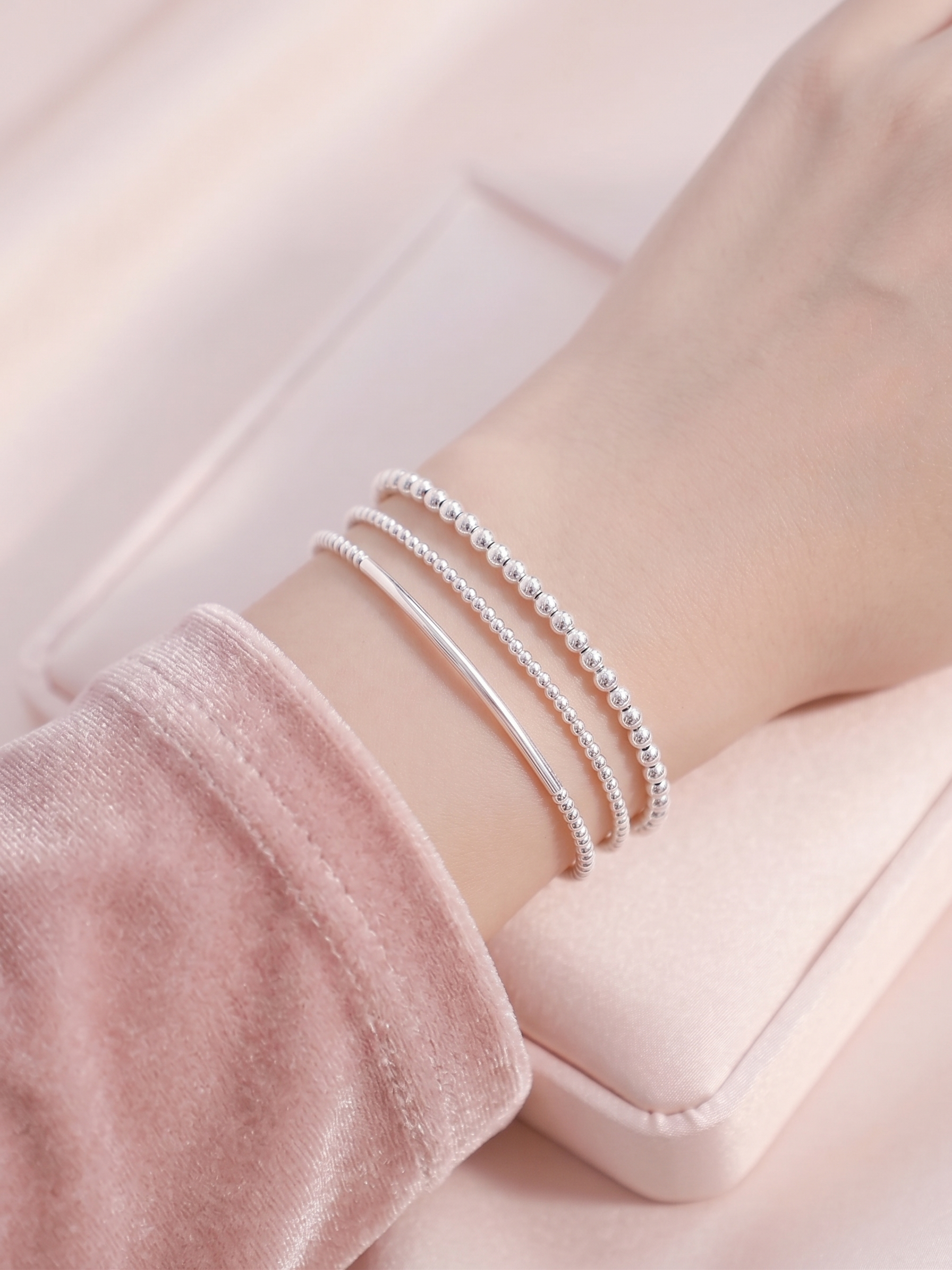 Stacked silver beaded stretch bracelets with smooth bars on wrist