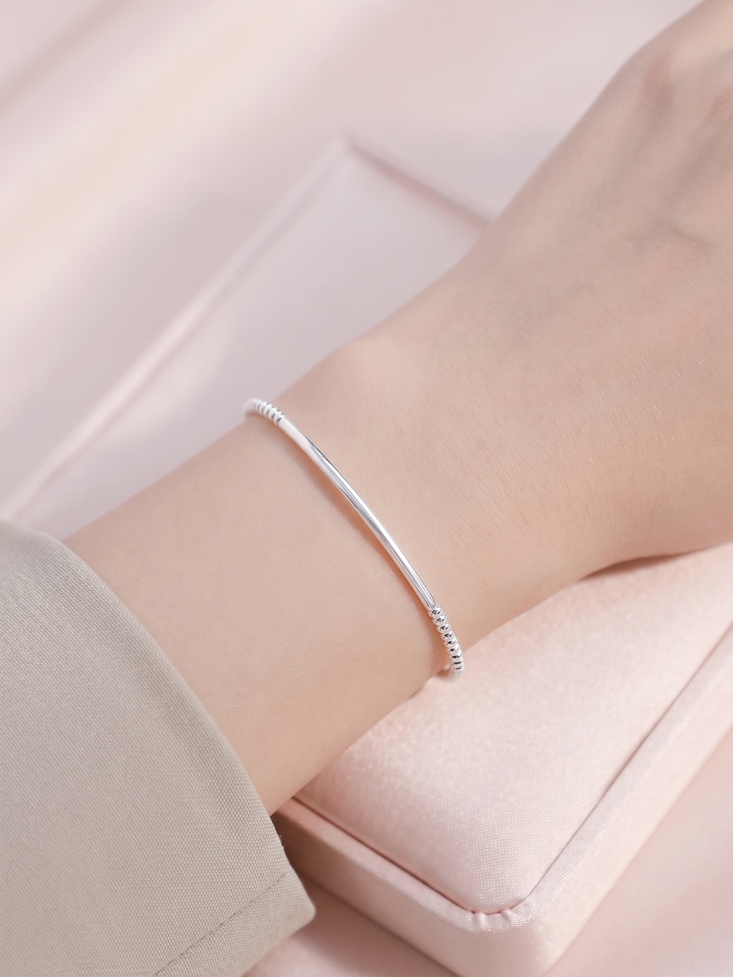 Silver beaded stretch bracelet on wrist with a smooth curved bar