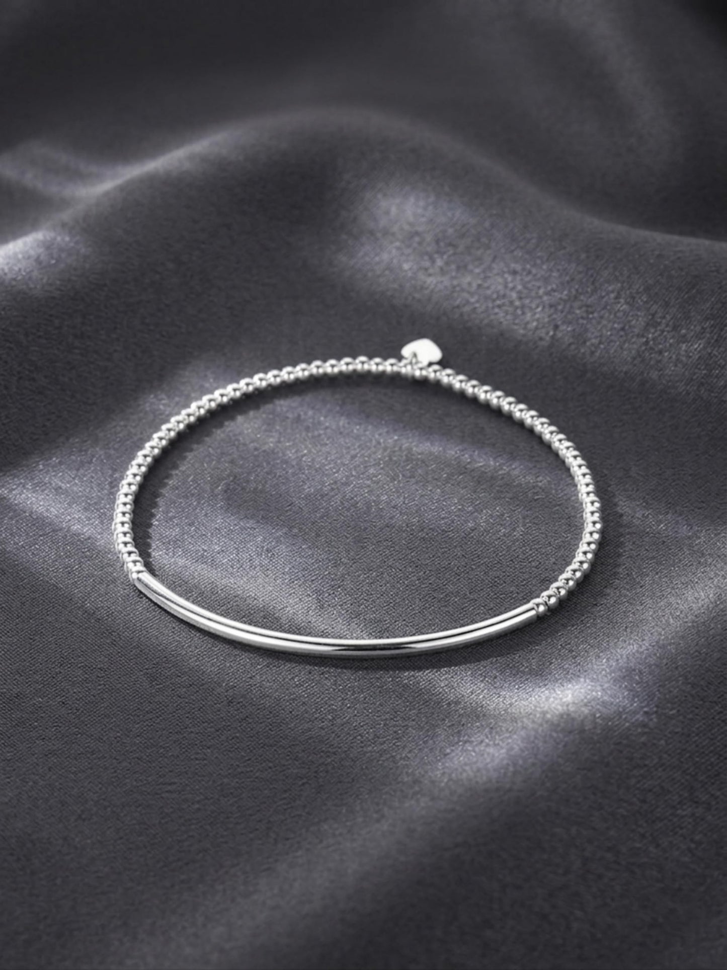 Silver beaded stretch bracelet with heart charm on a smooth curved bar