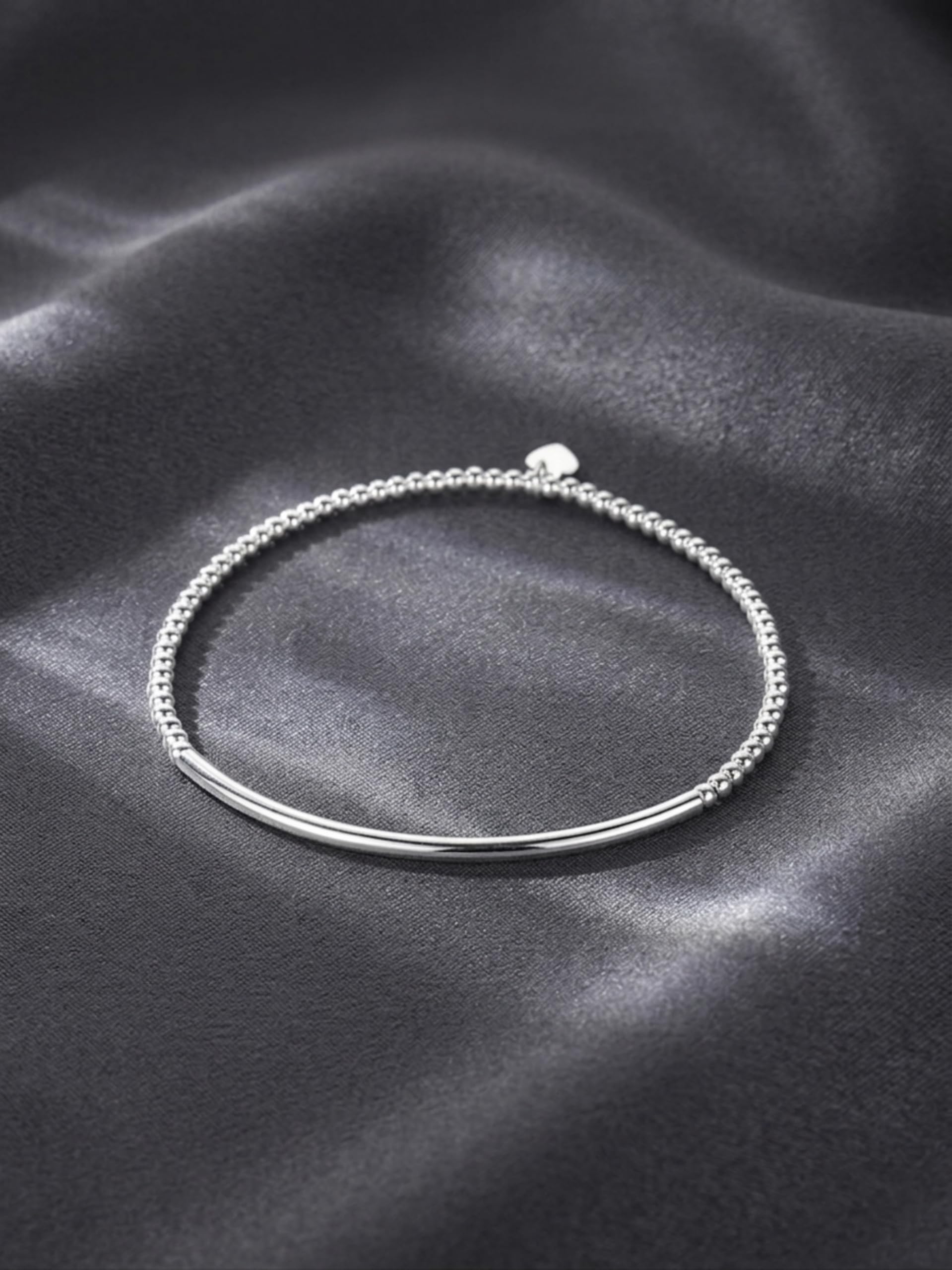 Silver beaded stretch bracelet with heart charm on a smooth curved bar