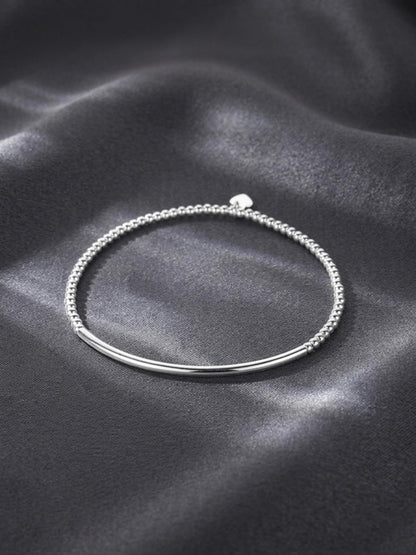 Silver beaded stretch bracelet with heart charm on a smooth curved bar