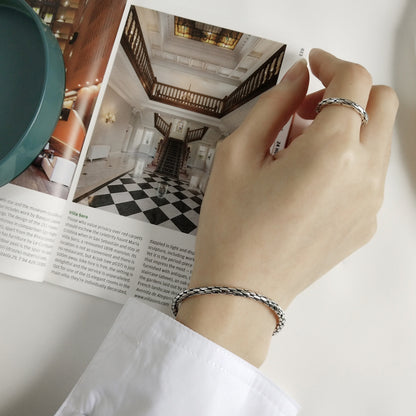 Snake-knot cuff bangle on wrist, silver-toned twisted braid cuff