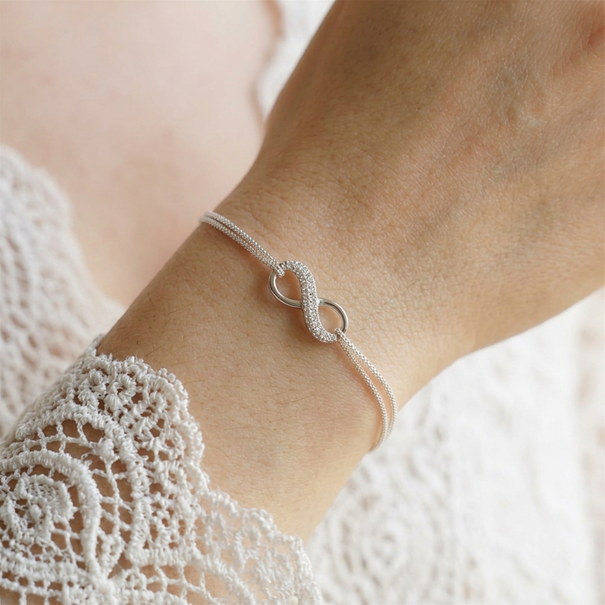 Silver infinity bracelet with linked oval charms and sparkling stones on wrist
