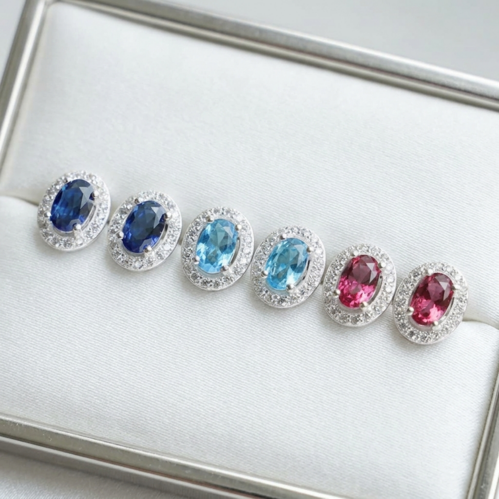 Oval halo CZ stud earrings lineup with blue and pink/red oval stones in silver-toned halos