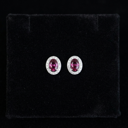Oval ruby-red CZ stud earrings with silver halo and small round stones