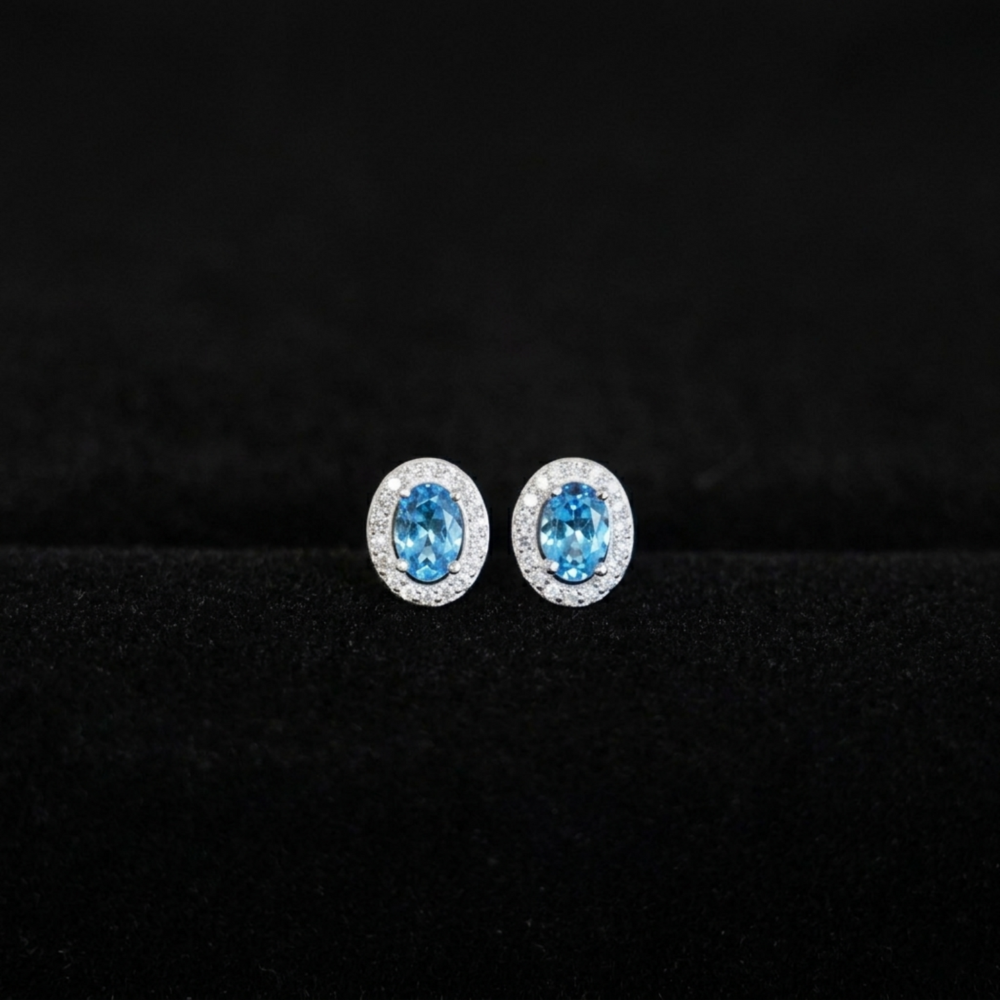 Oval halo CZ stud earrings with light blue oval stones and glittery silver halos