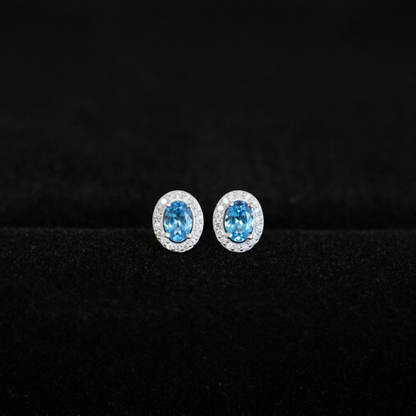 Oval halo CZ stud earrings with light blue oval stones and glittery silver halos
