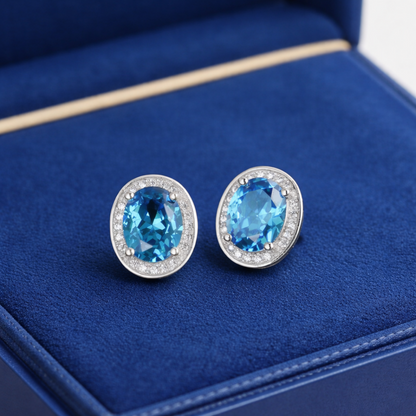Round blue gemstone stud earrings with CZ halo border, silver-tone posts