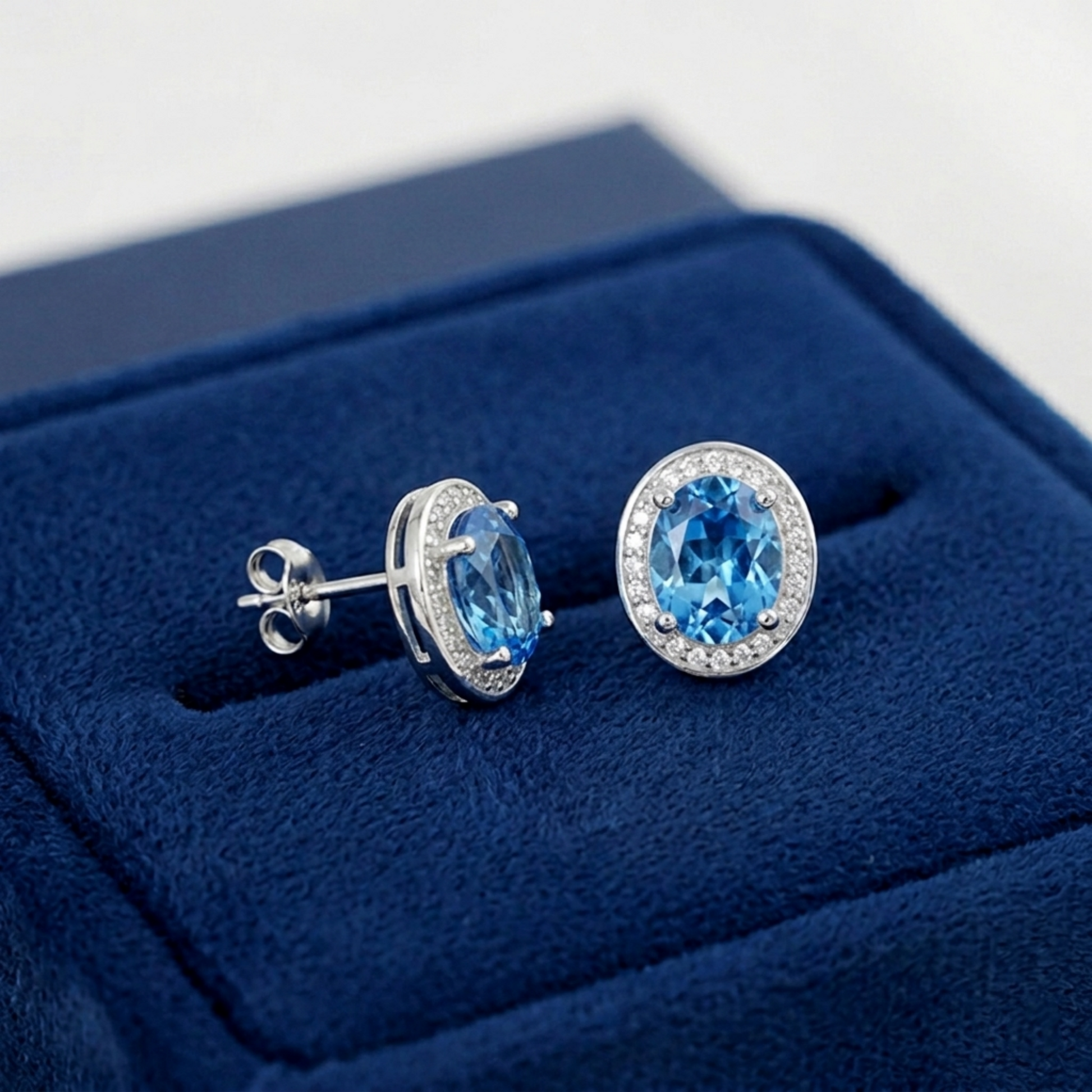 Silver-tone stud earrings with blue gemstones and CZ halos, backs visible