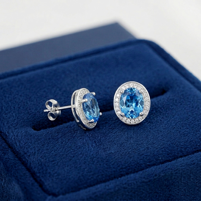 Silver-tone stud earrings with blue gemstones and CZ halos, backs visible