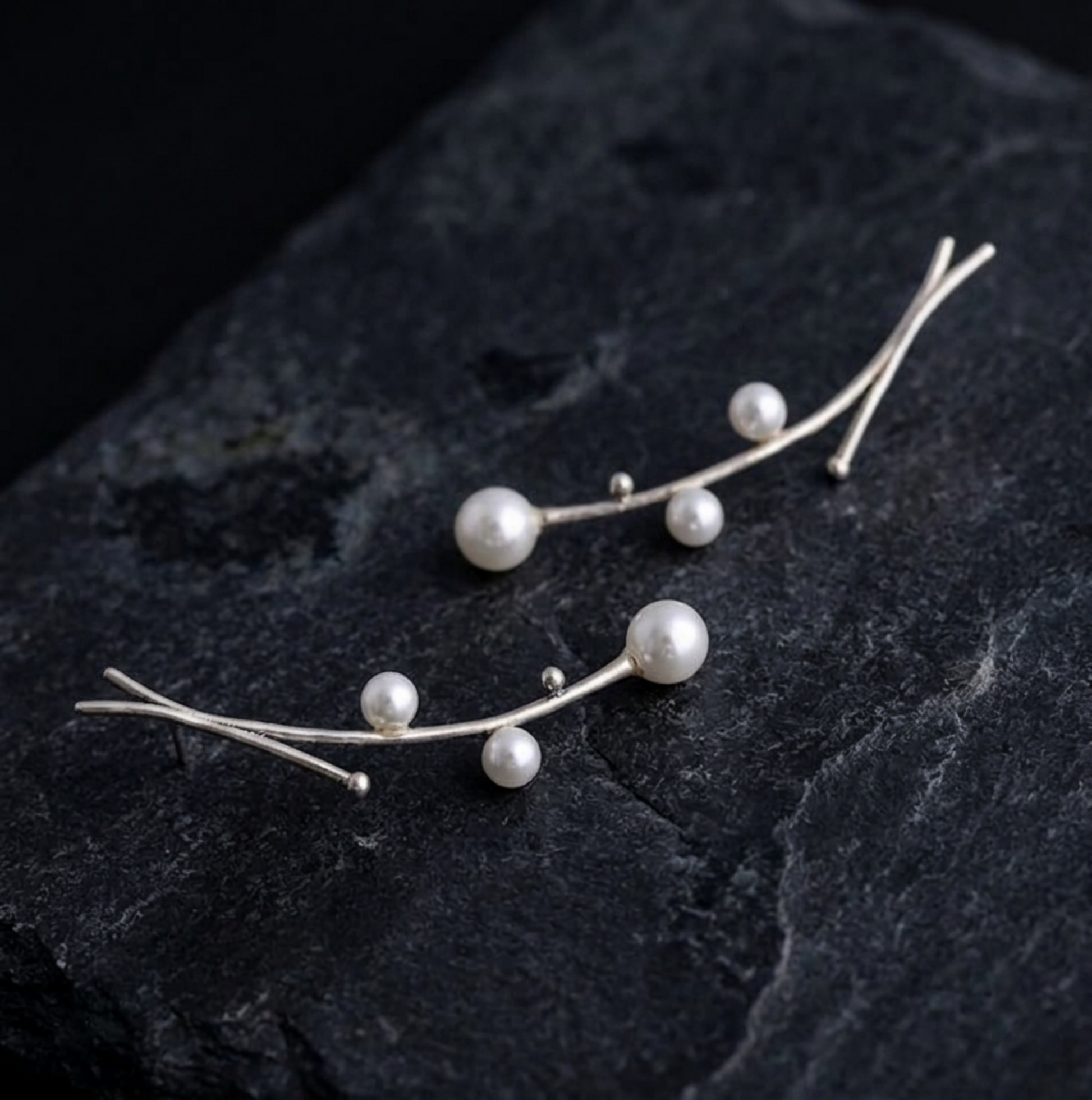 Pearl drop earrings on dark stone: small white pearls on silver wire branches