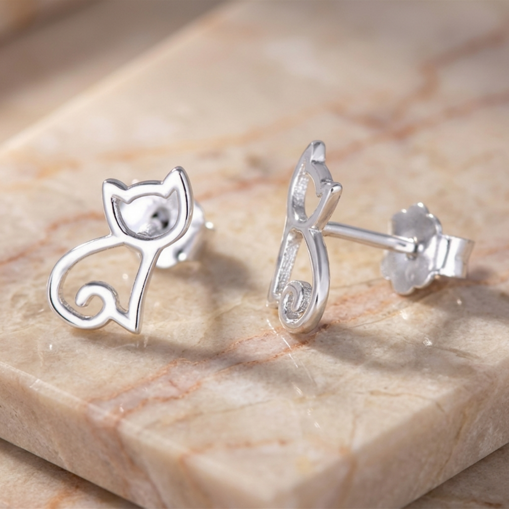 Cat-shaped silver stud earrings shown from side with pin backs