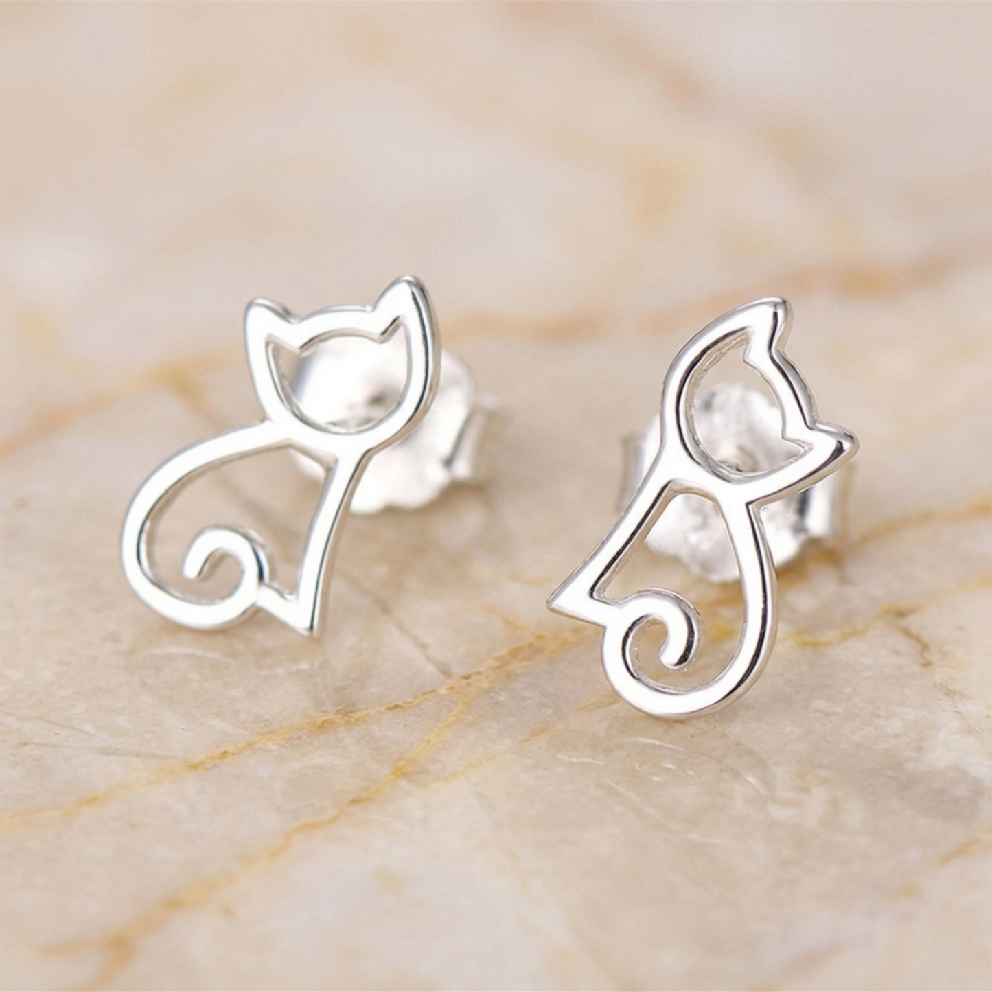 Silver cat-outline stud earrings with cat face and curled tail