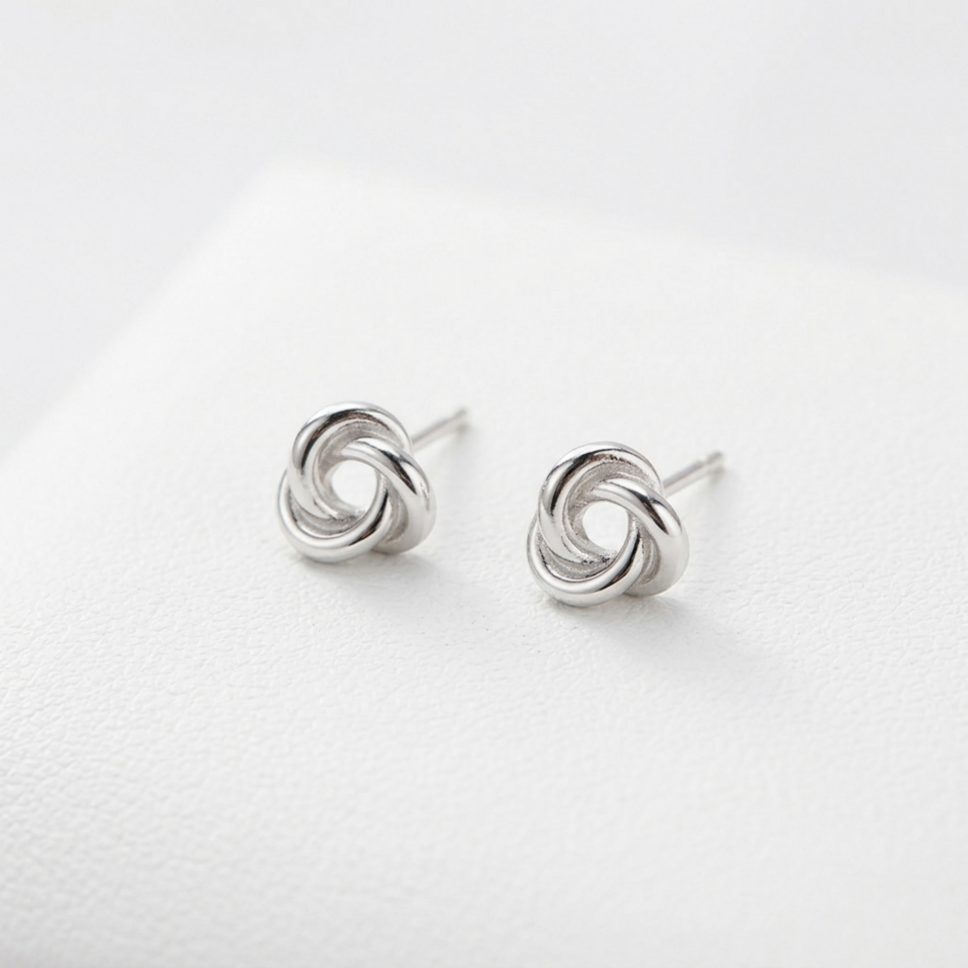 Silver knot stud earrings pair, circular trinity swirl front view