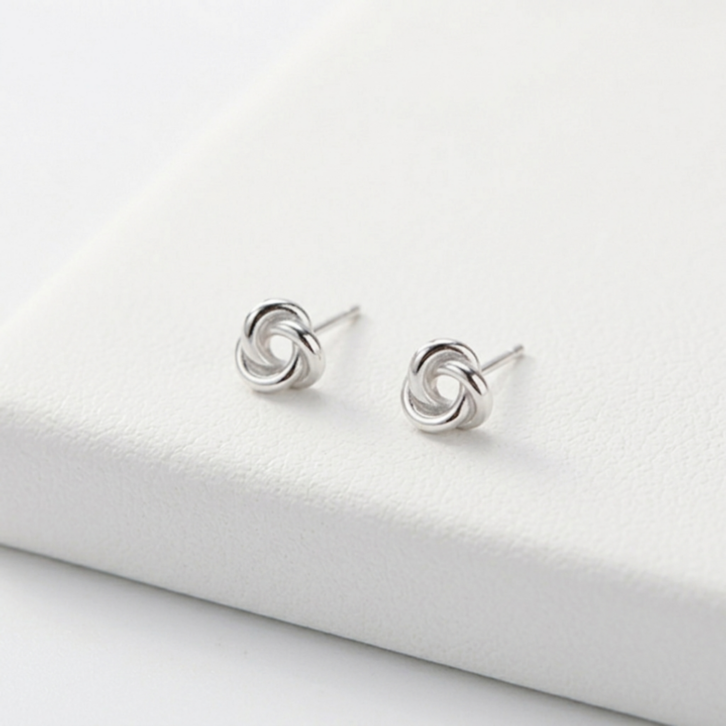 Silver knot stud earrings on display, visible stud posts