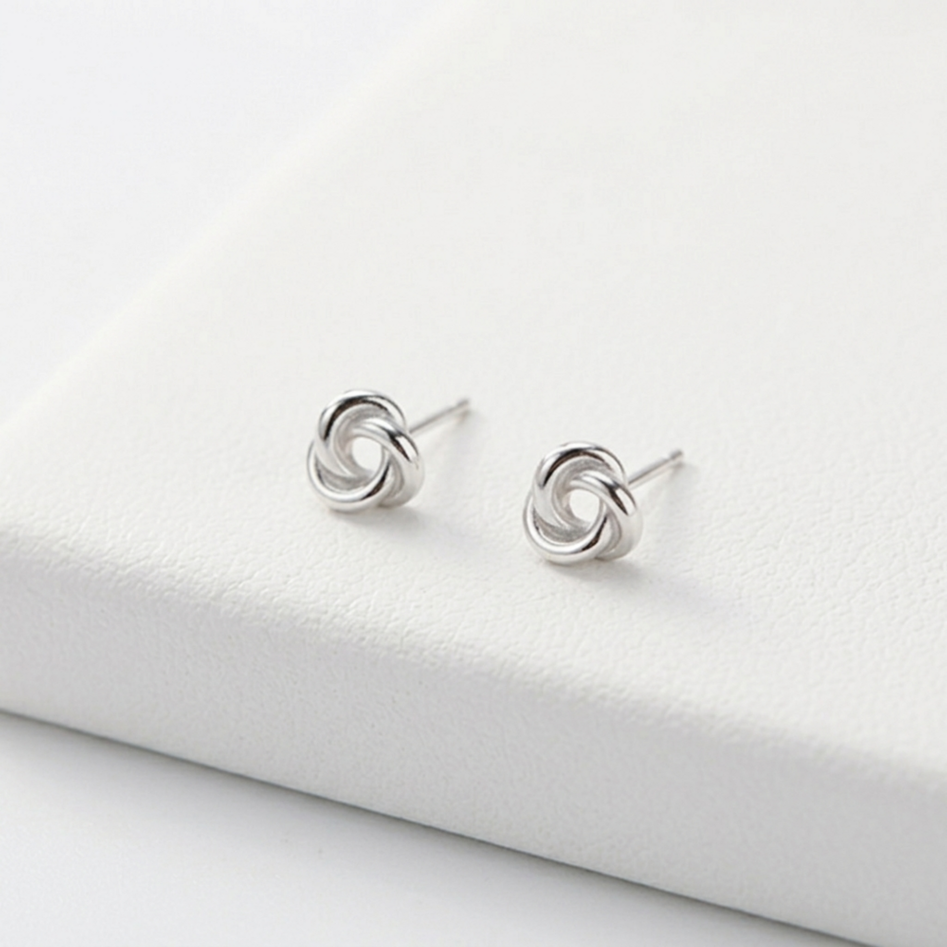 Silver knot stud earrings on display, visible stud posts