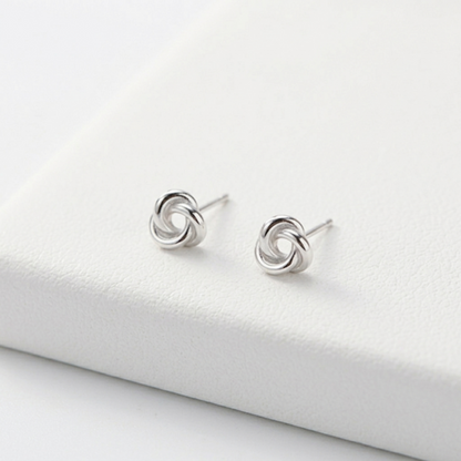 Silver knot stud earrings on display, visible stud posts
