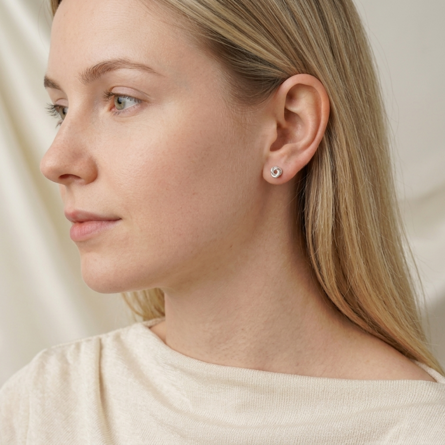 Silver knot stud earrings on blonde model, small round swirl studs
