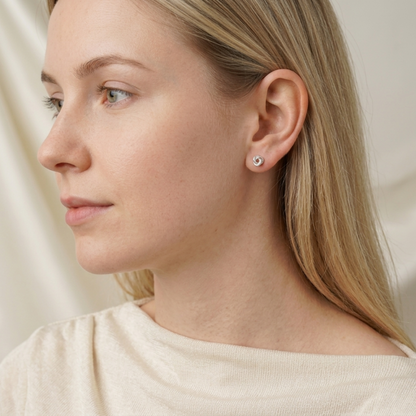 Silver knot stud earrings on blonde model, small round swirl studs