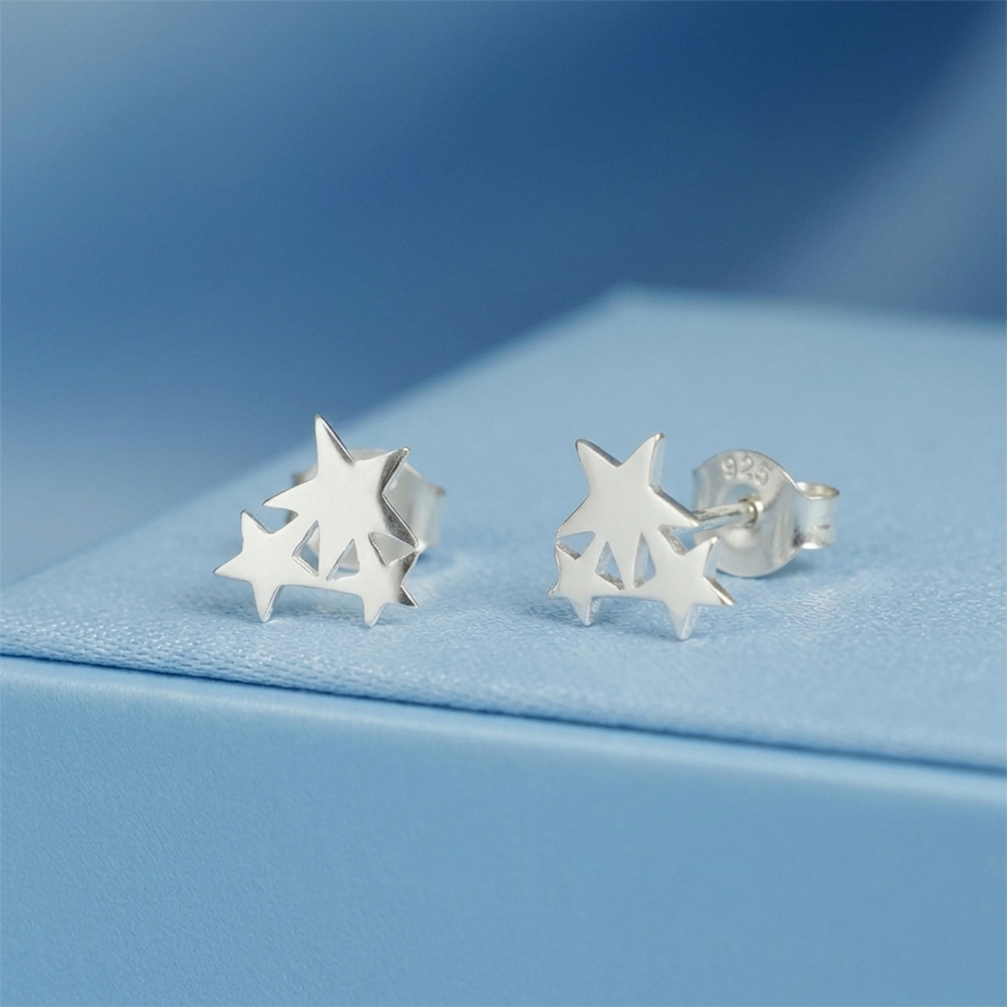 Silver triple star stud earrings with star cutouts, angled view