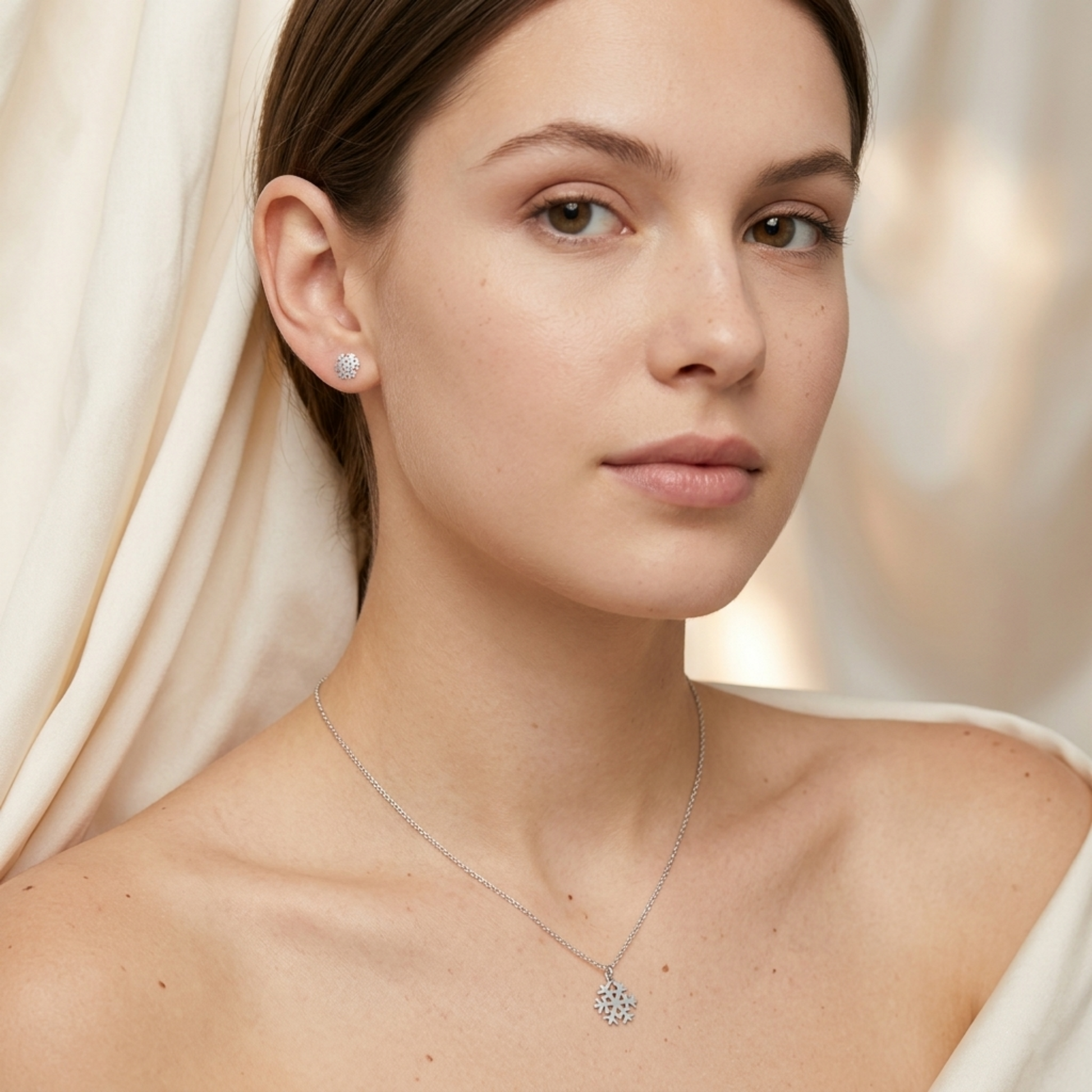 Silver snowflake stud earrings on model's ear