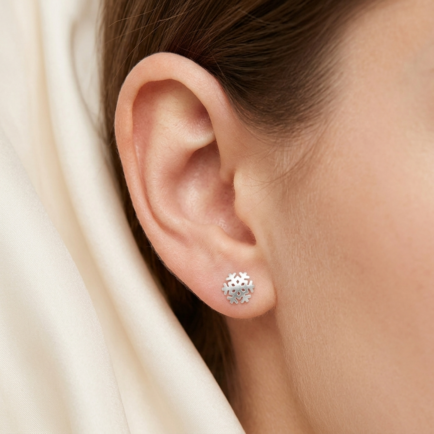 Snowflake stud earring on ear, silver finish