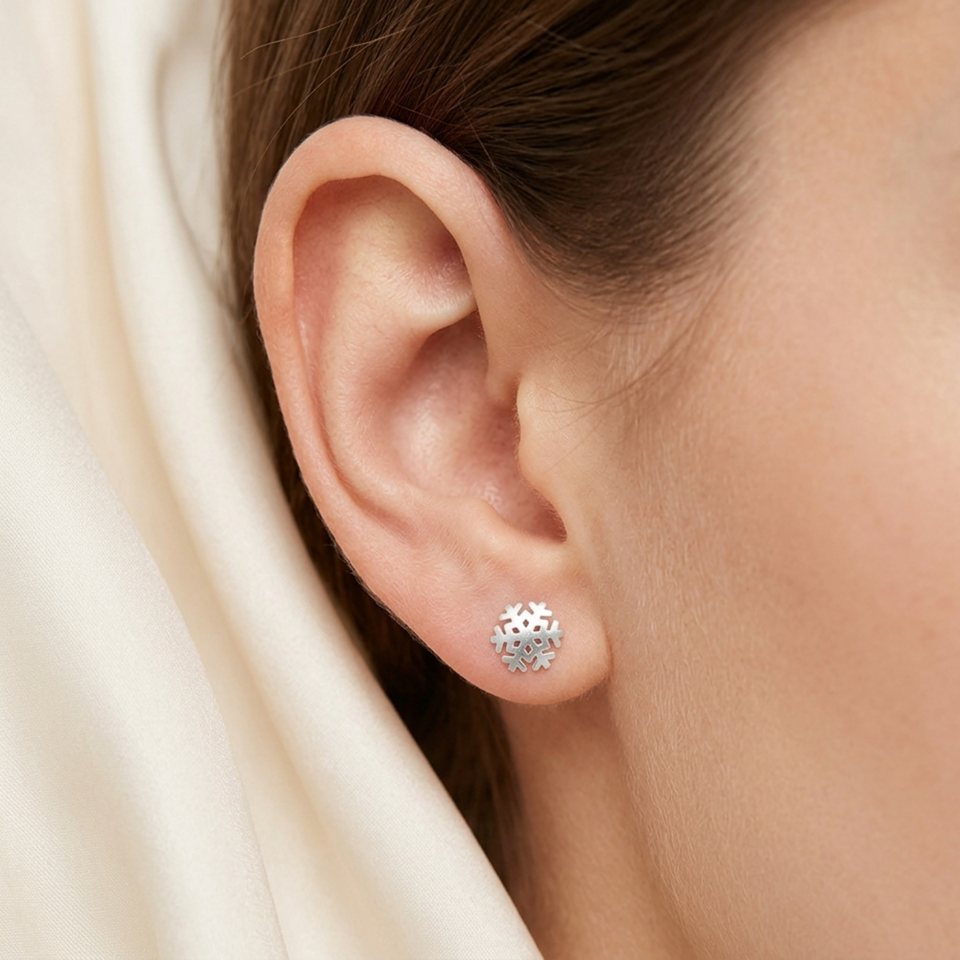 Snowflake stud earring on ear, silver finish