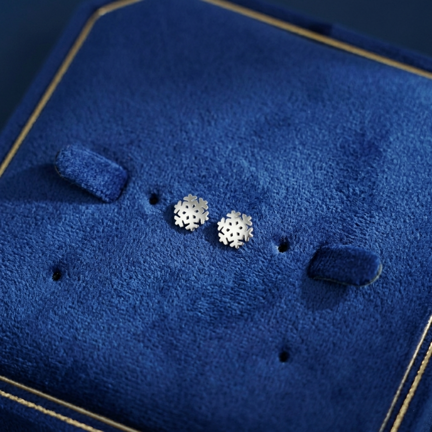 Silver snowflake stud earrings on jewelry display pad