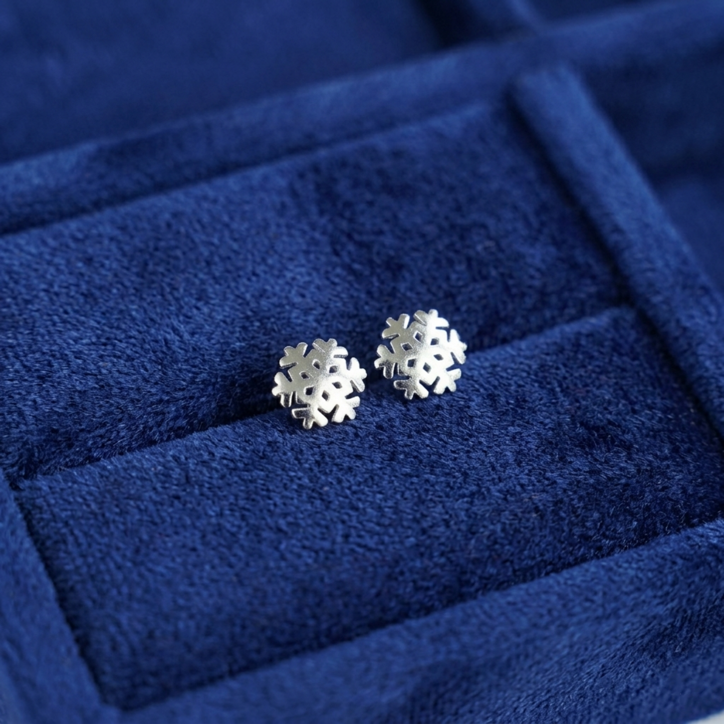 Silver snowflake stud earrings on velvet ring box