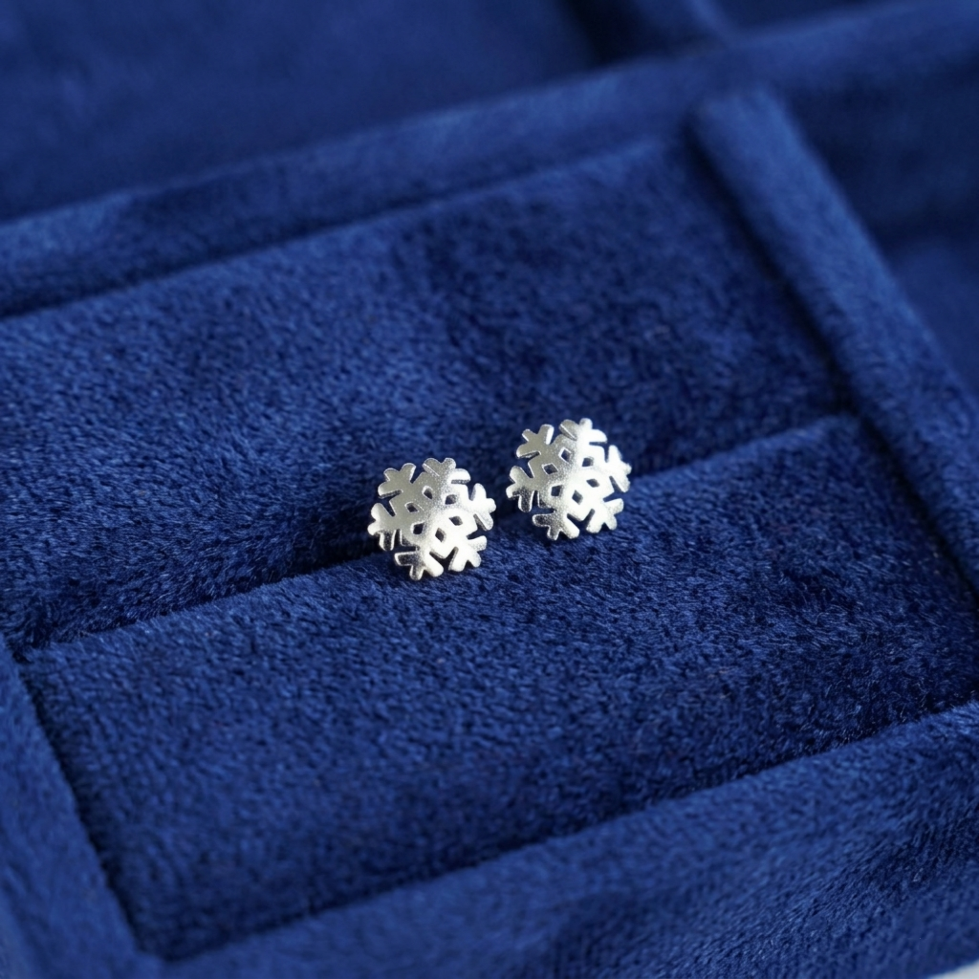 Silver snowflake stud earrings on velvet ring box