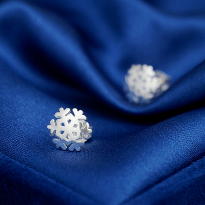 Silver snowflake stud earrings on fabric