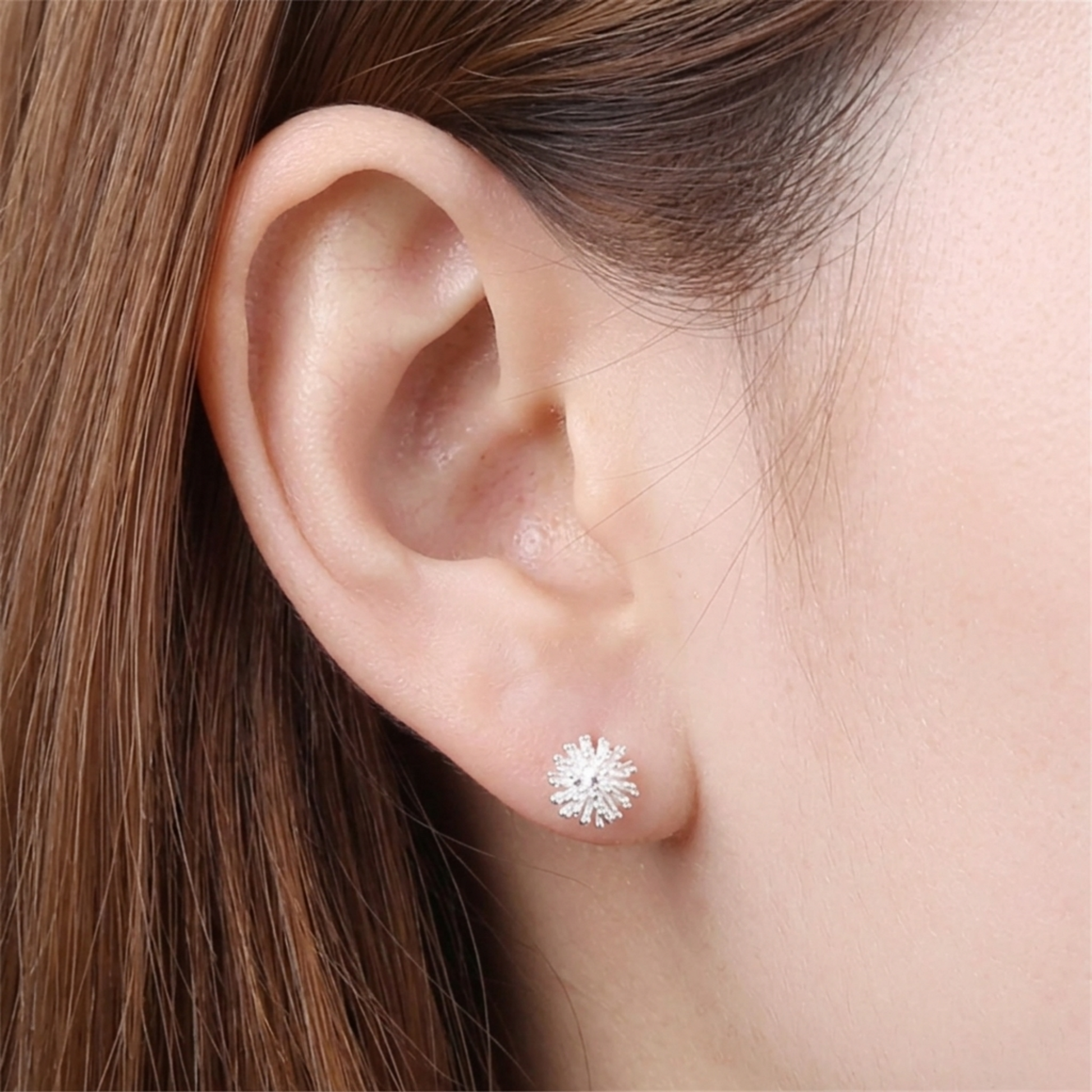 Silver-toned dandelion flower stud earring on model ear with small sparkly petals
