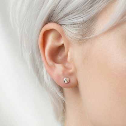 Cone spike stud earrings on ear, silver-tone pointed circular stud tops