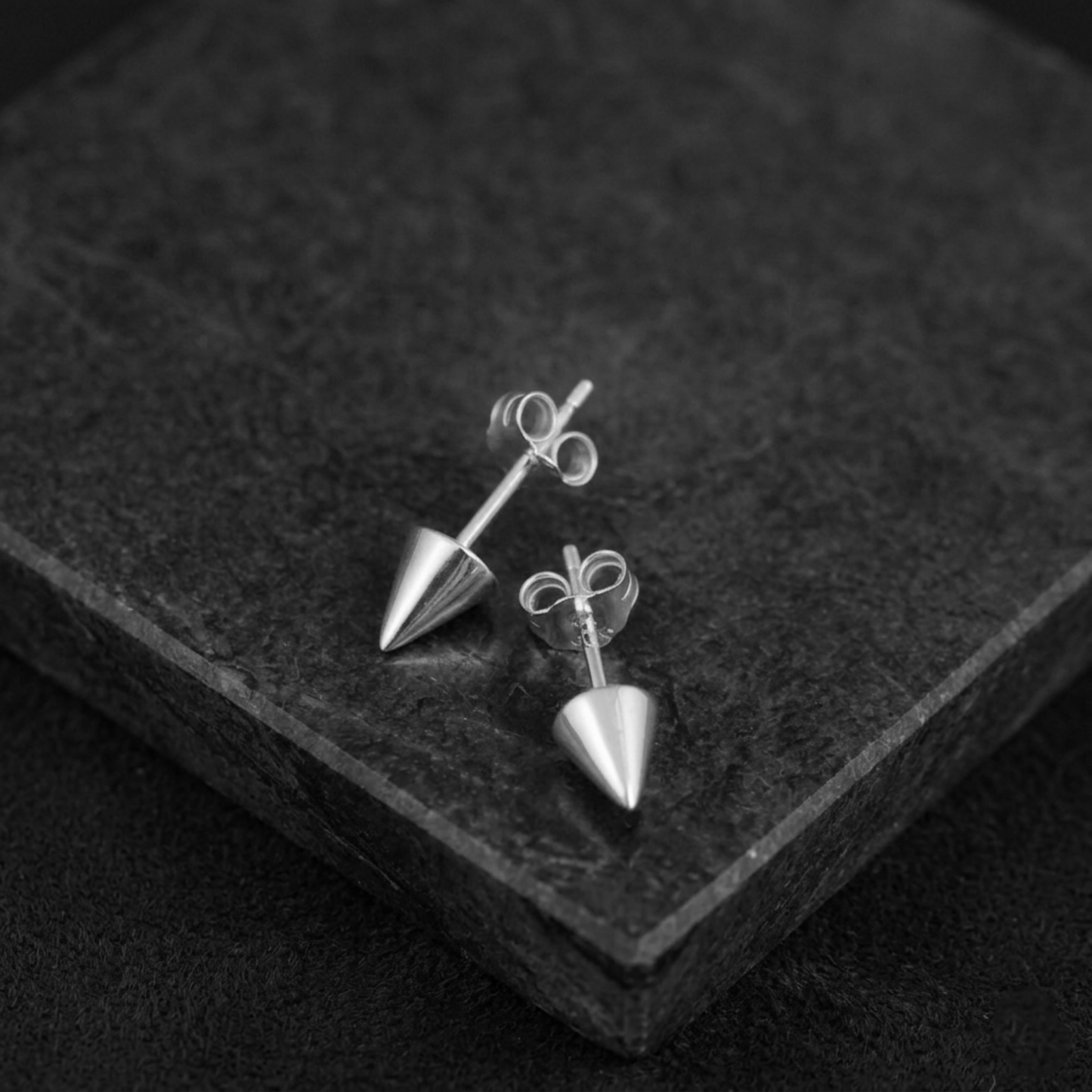 Silver-tone cone spike stud earrings on a display card, with butterfly backings