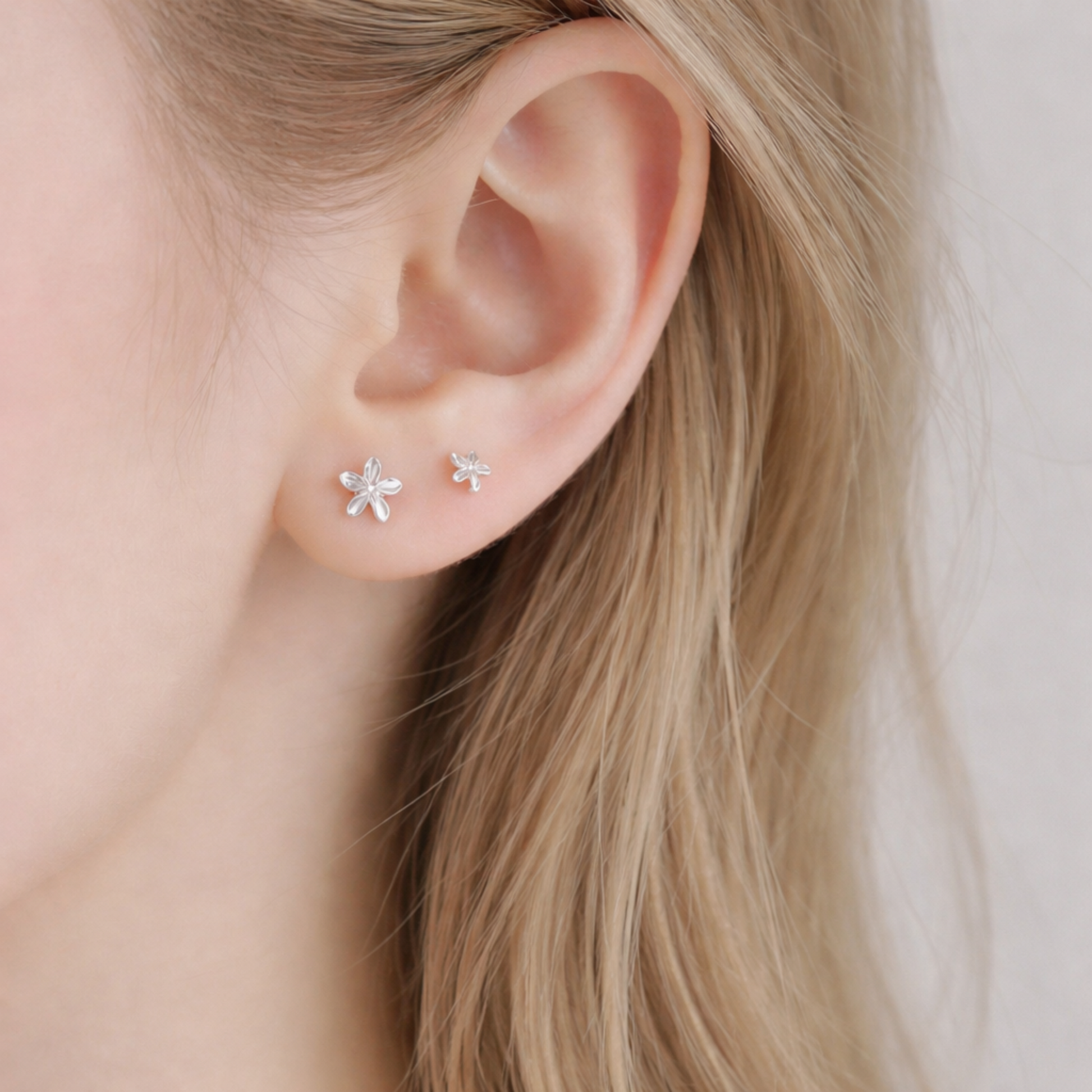 Silver lily flower stud earrings worn on ear