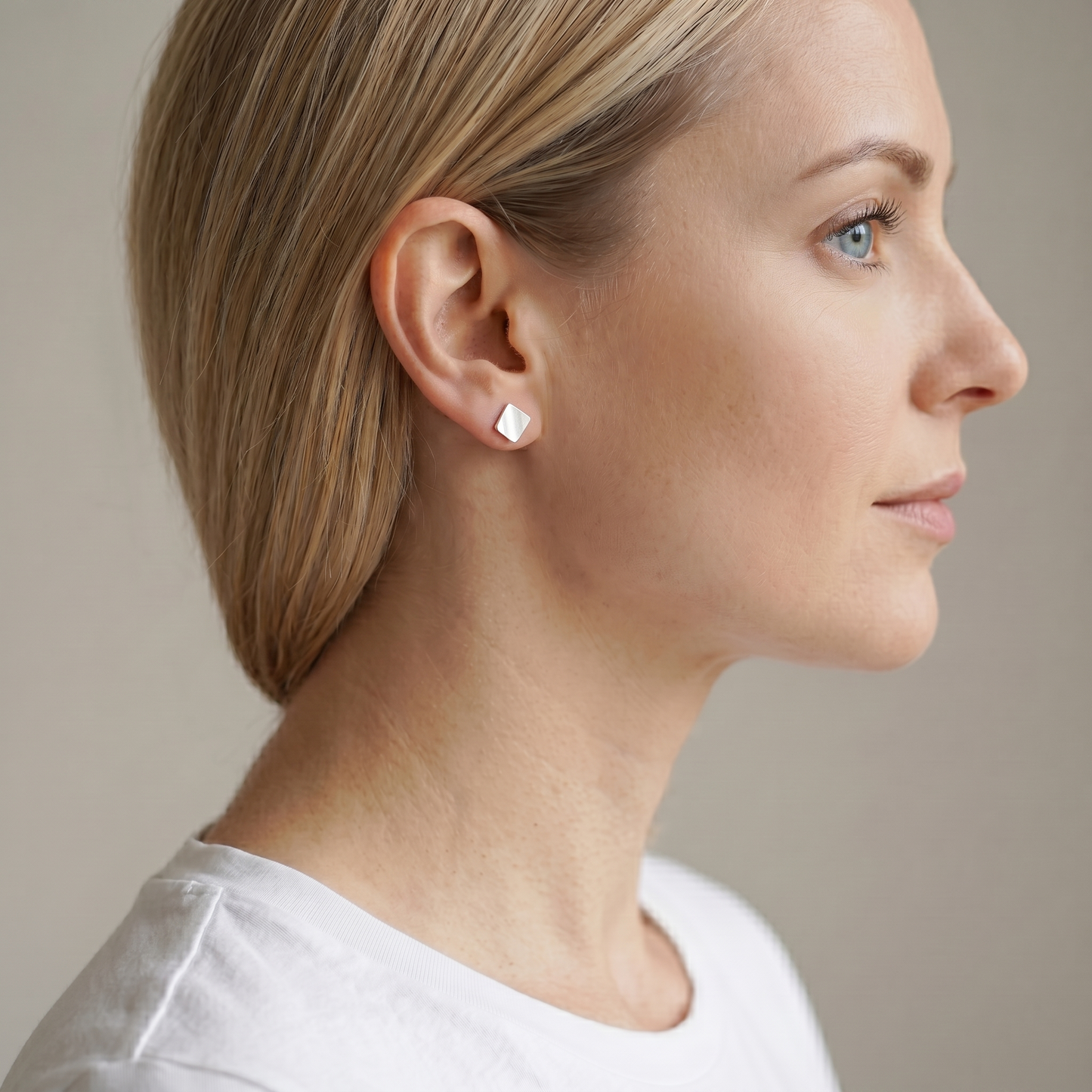 Matte cube stud earrings on ear, silver brushed cube studs, small size.