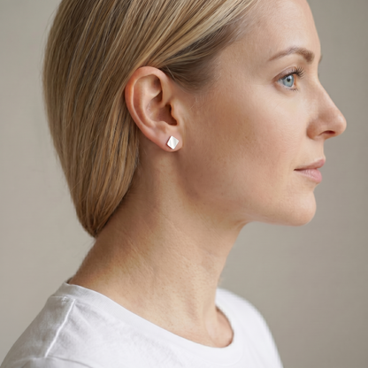 Matte cube stud earrings on ear, silver brushed cube studs, small size.