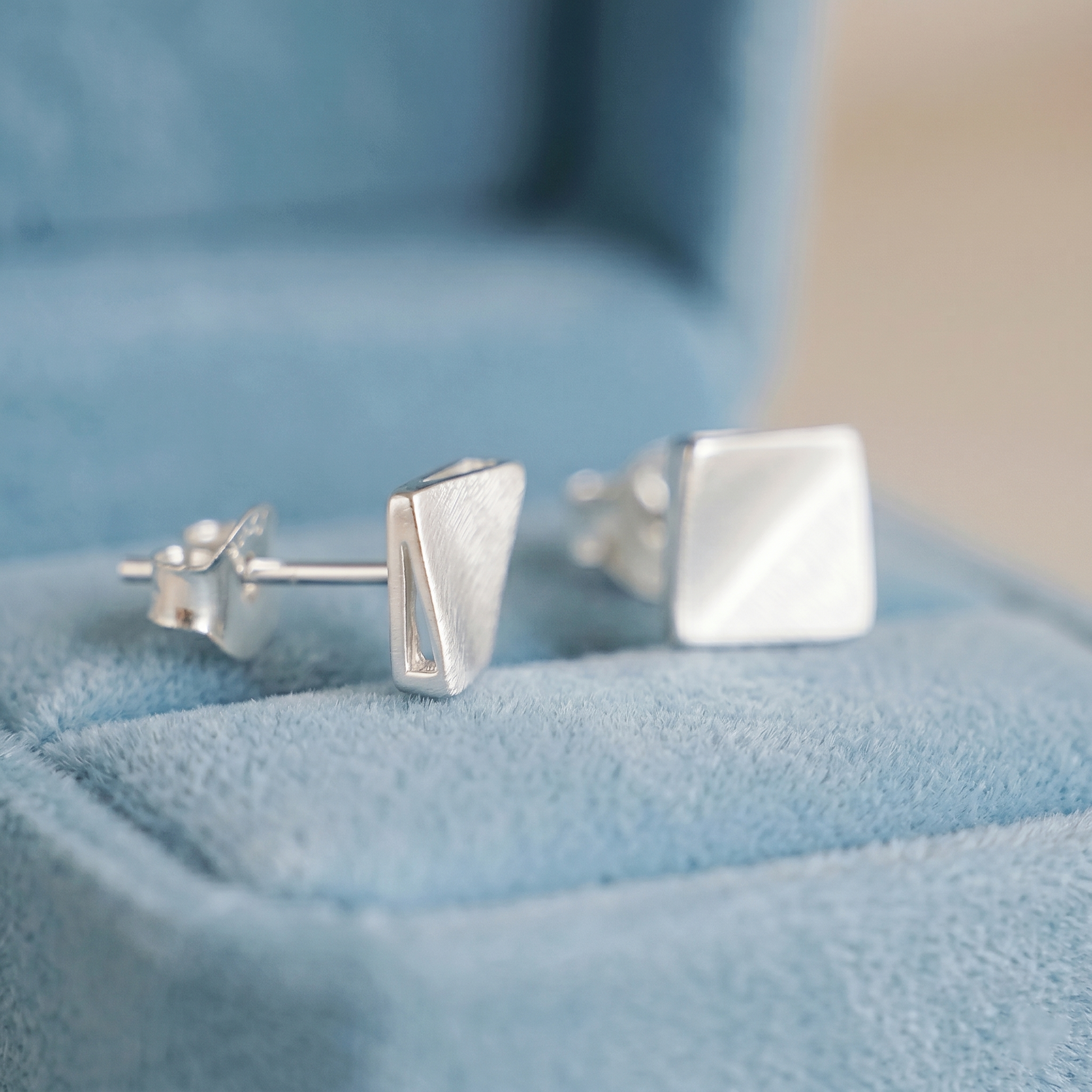 Matte cube stud earrings from side view, brushed silver square studs.