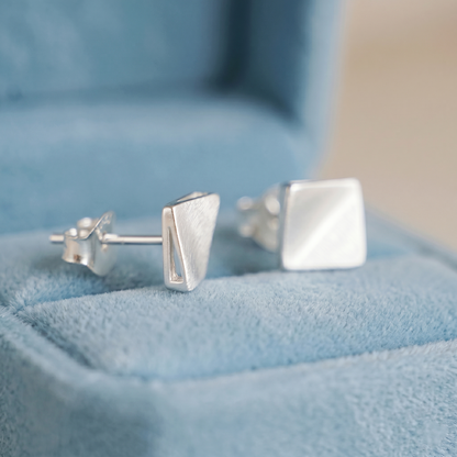 Matte cube stud earrings from side view, brushed silver square studs.