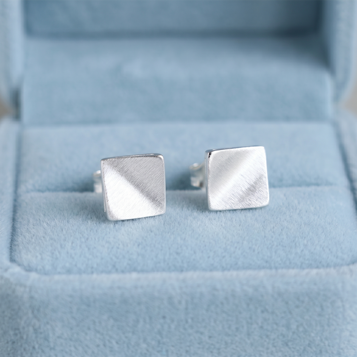 Matte cube stud earrings in brushed silver on visible post backs.