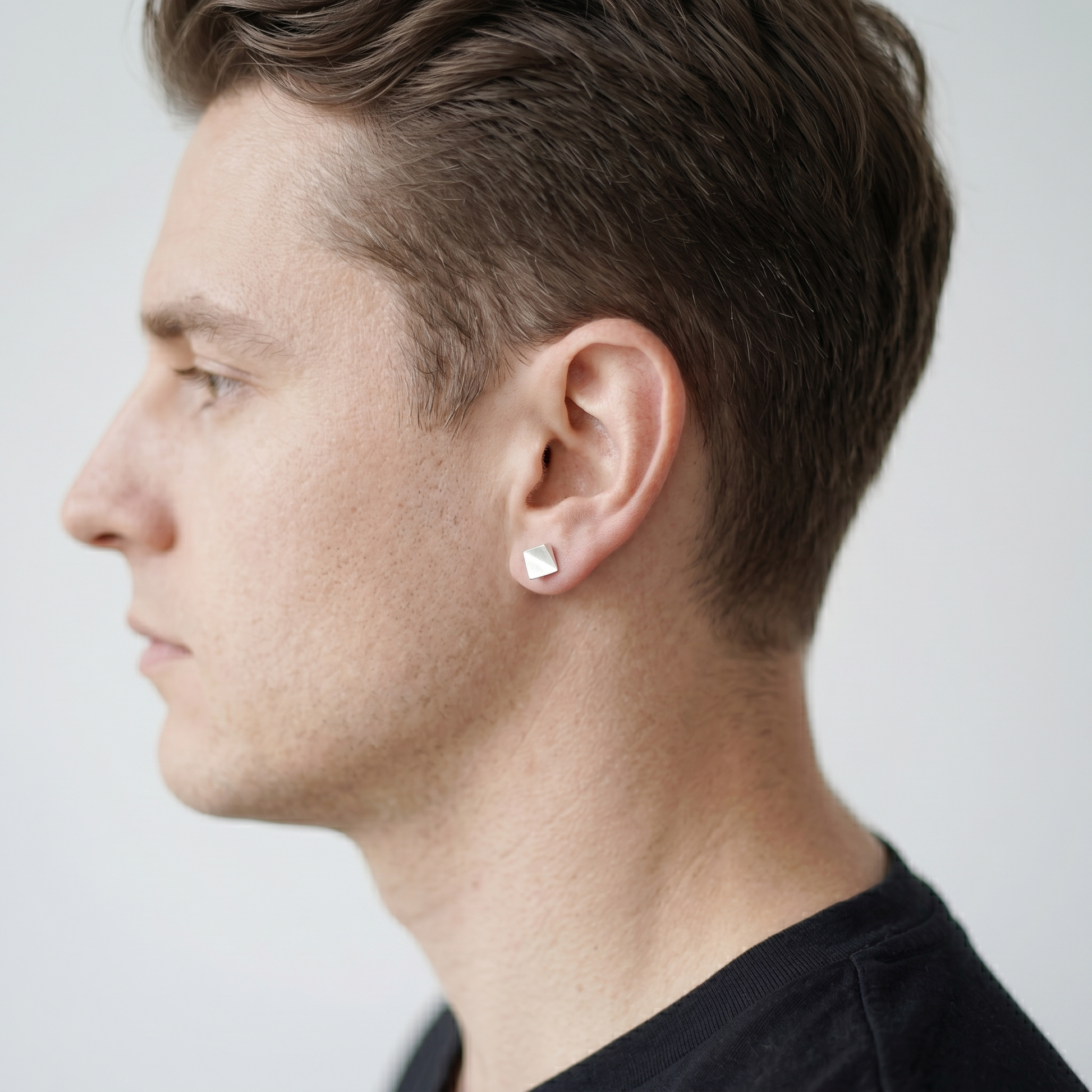 Matte cube stud earrings on ear, silver square studs with posts.