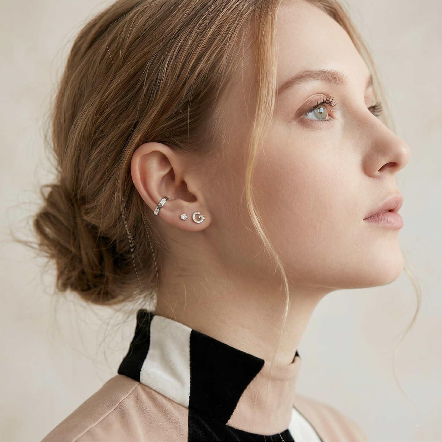 Letter G stud earrings, silver-tone, on model's ear