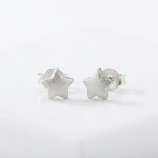 Silver puffy star stud earrings on a white background