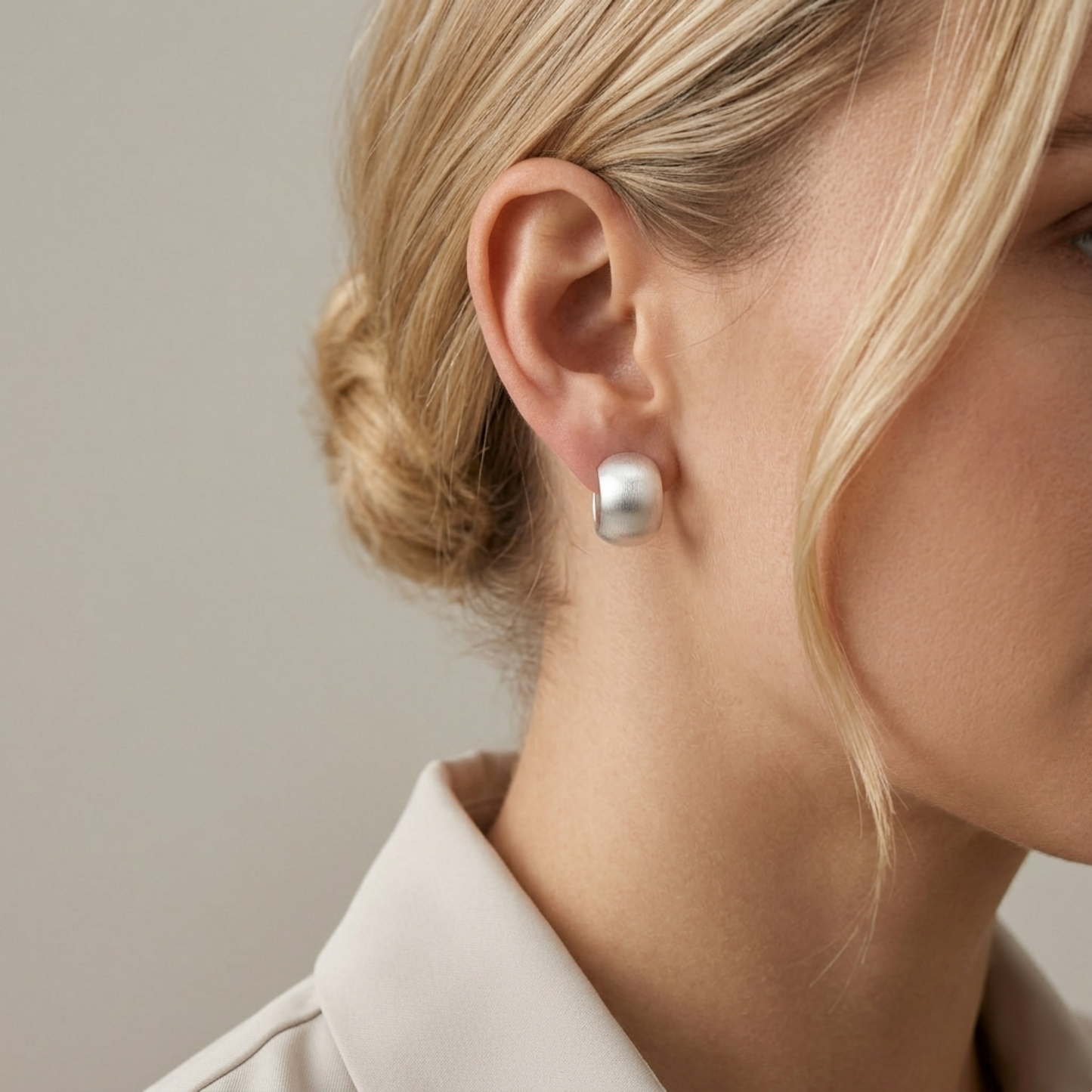 Brushed half-hoop drop earrings on model, silver-tone circular half-hoop style.