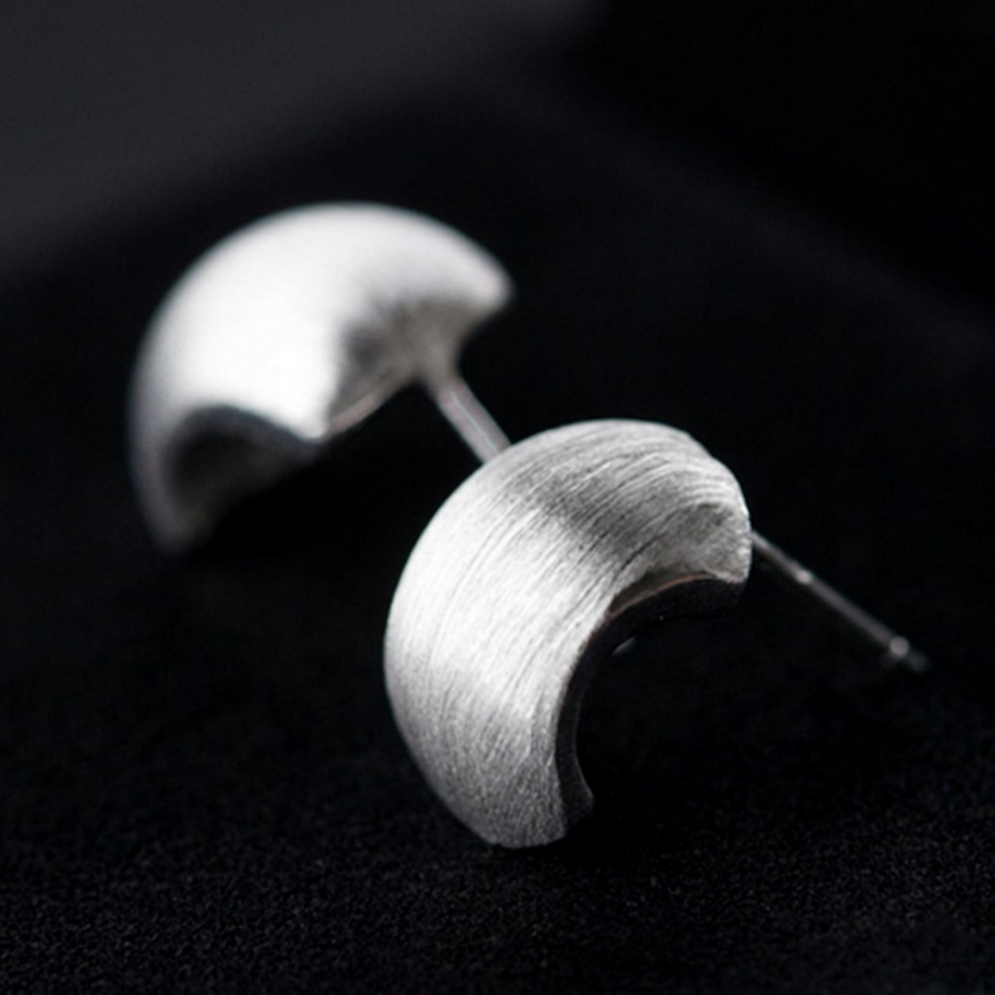 Brushed half-hoop drop earrings with silver-tone curved half-hoop and post, angled view.