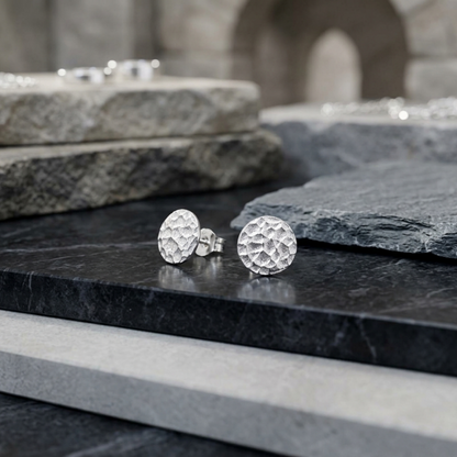 Silver hammered disc stud earrings on dark stone surface