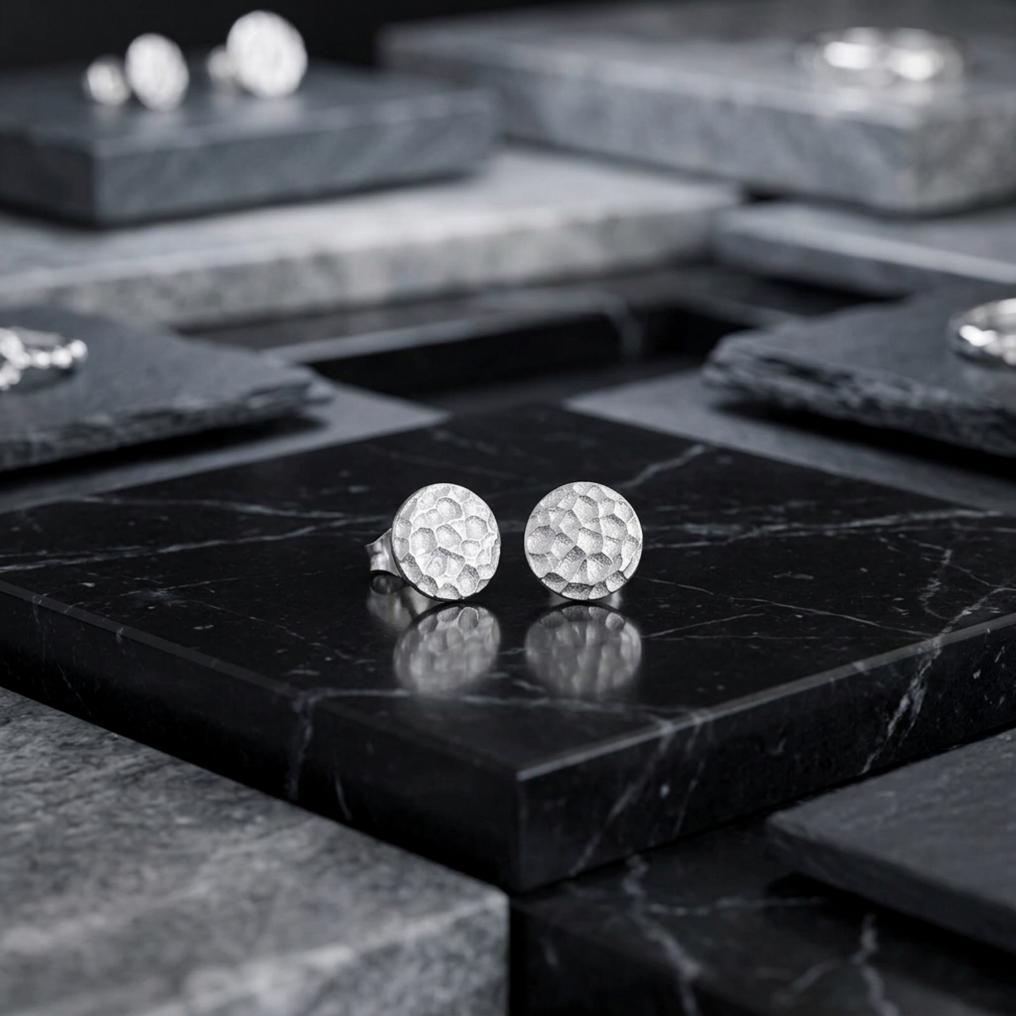 Silver hammered disc stud earrings with textured round discs on black marble