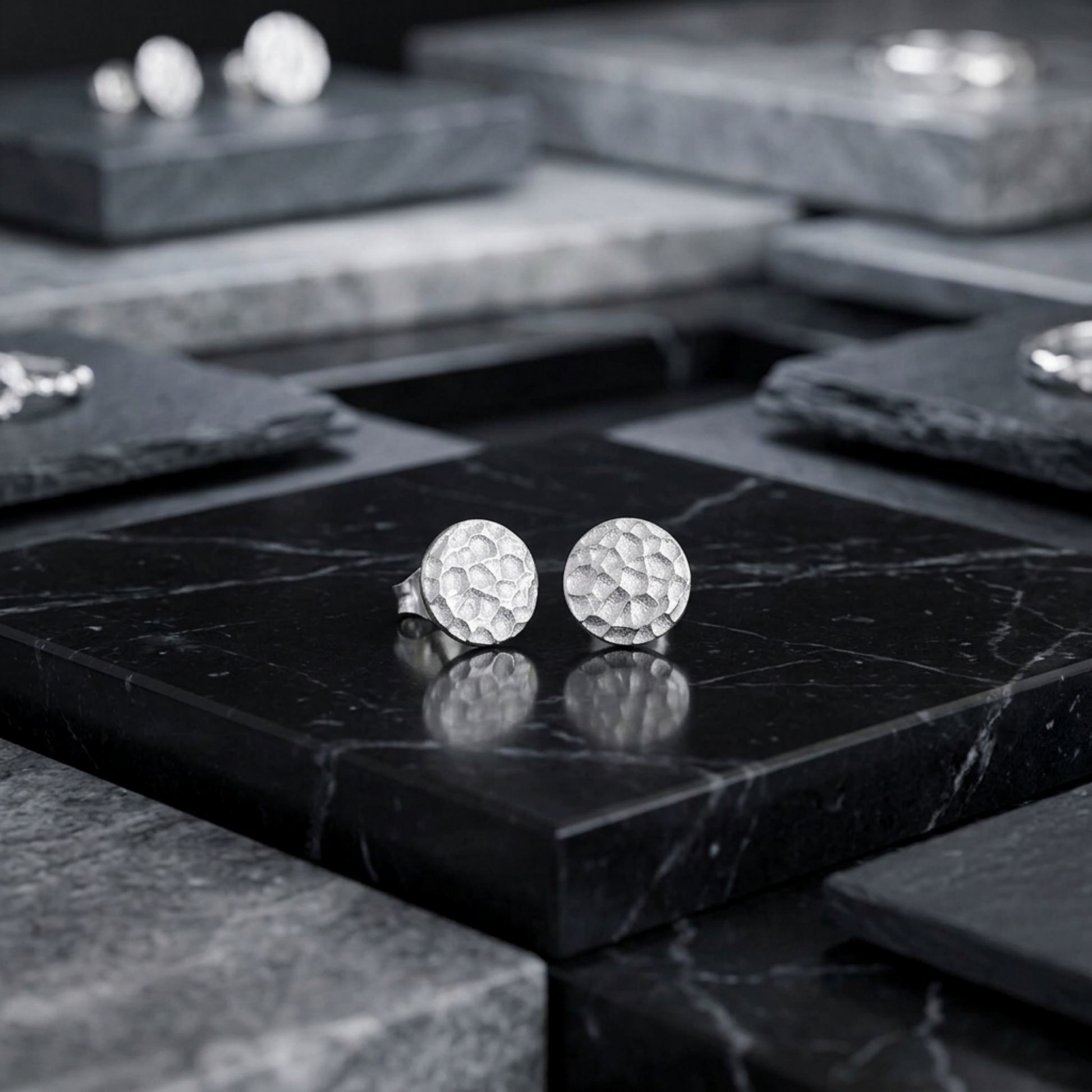 Silver hammered disc stud earrings with textured round discs on black marble