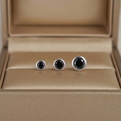 Bezel solitaire stud earrings, three-quarter view of round black stones in bezel settings